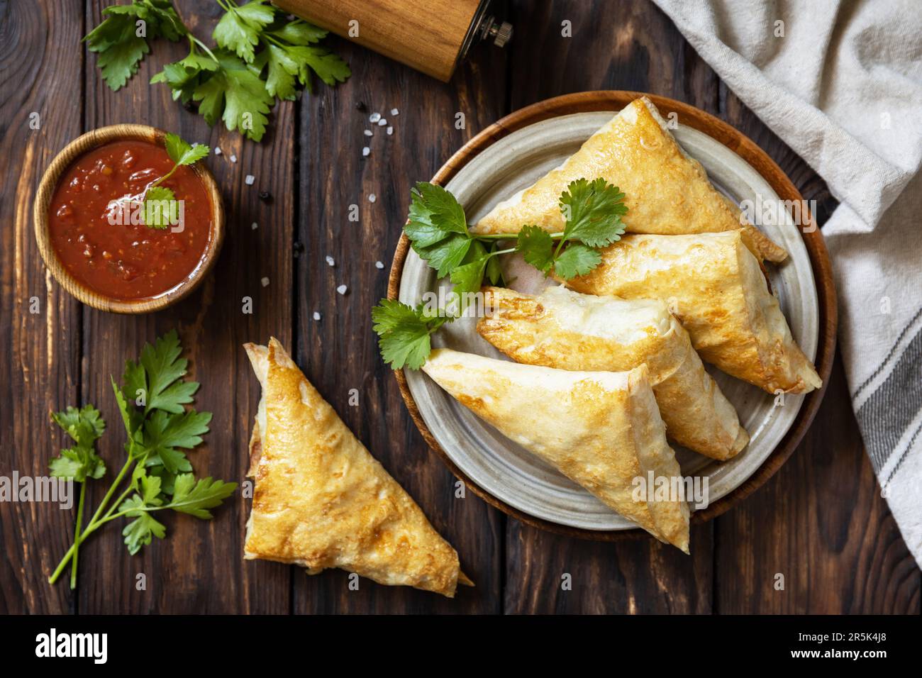 Asiatisches Essen. Vegetarische samsa (Samosas) mit Tomatensoße auf einem Holztisch. Beliebt in Indonesien als Risoles Sayur. Blick von oben. Stockfoto