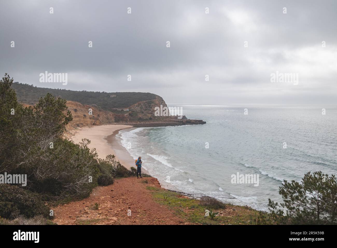 Wanderer stehen am Rand einer Klippe und beobachten den Strand unter dem Namen Praia do Burgau an der Südwestküste Portugals in touristischer und berühmter Weise Stockfoto