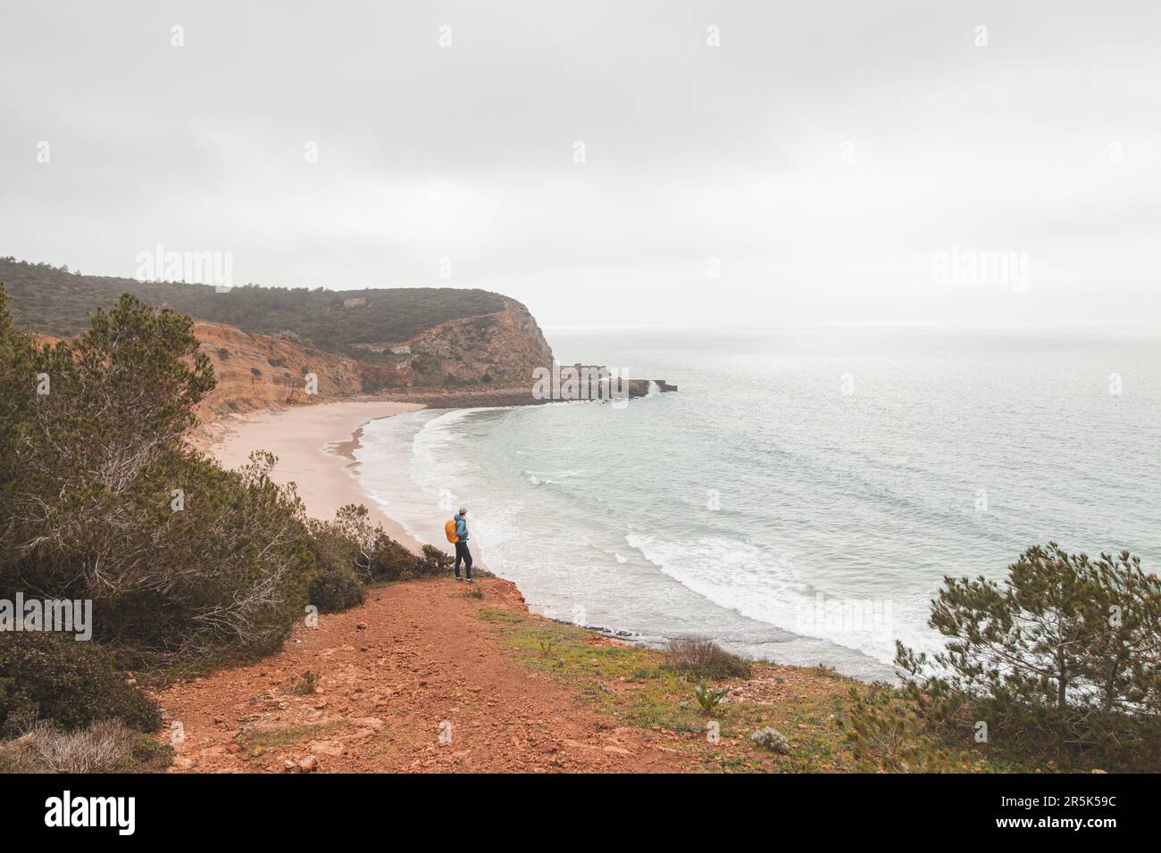 Wanderer stehen am Rand einer Klippe und beobachten den Strand unter dem Namen Praia do Burgau an der Südwestküste Portugals in touristischer und berühmter Weise Stockfoto