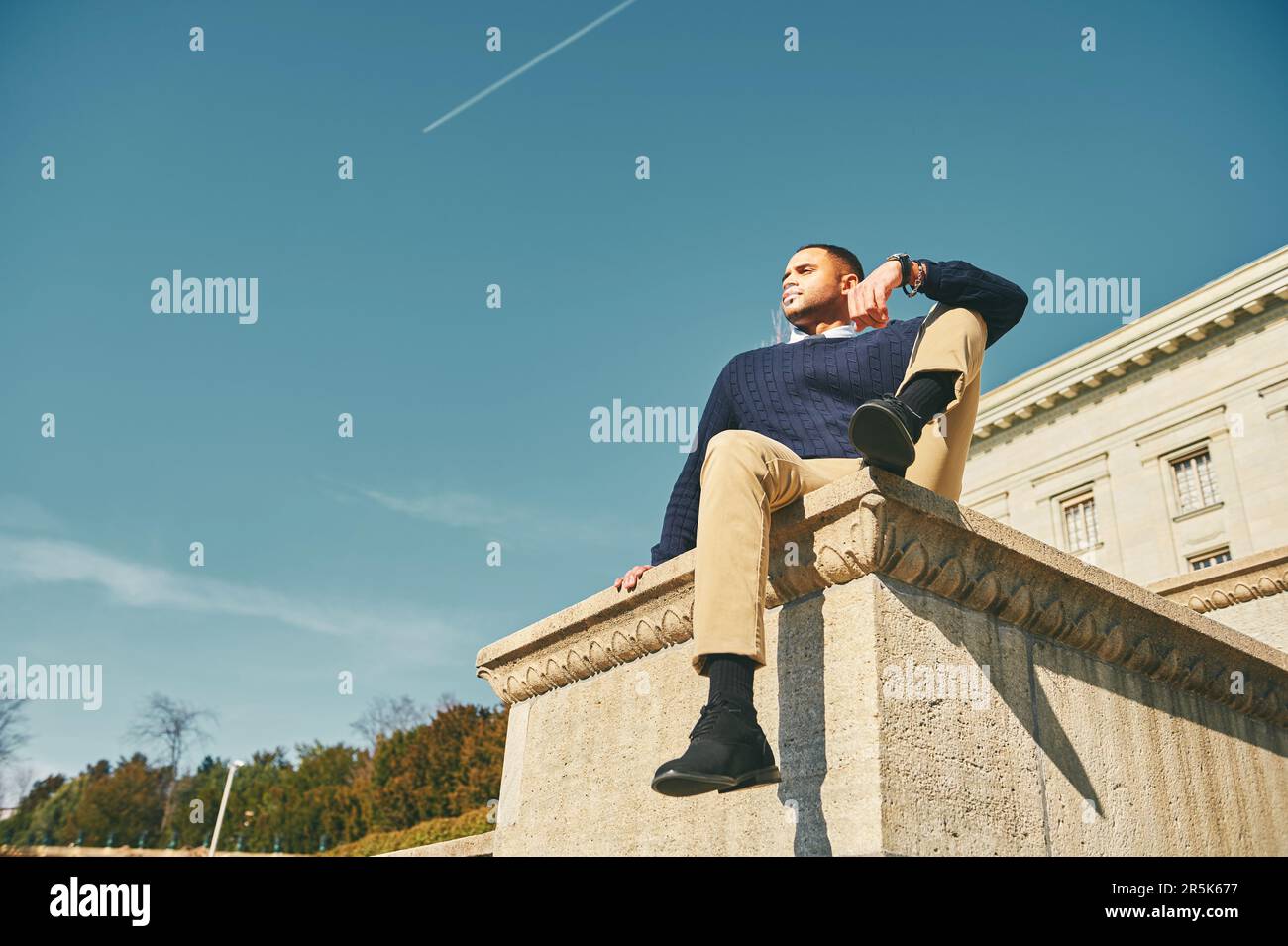 Außenporträt eines gutaussehenden afroamerikanischen männlichen Models, Posen gegen den Himmel, Männermode Stockfoto