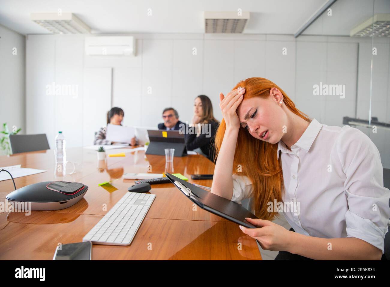 Eine gestresste Geschäftsfrau auf der Arbeit berührt ihre Stirn, überlastet auf der Arbeit Stockfoto