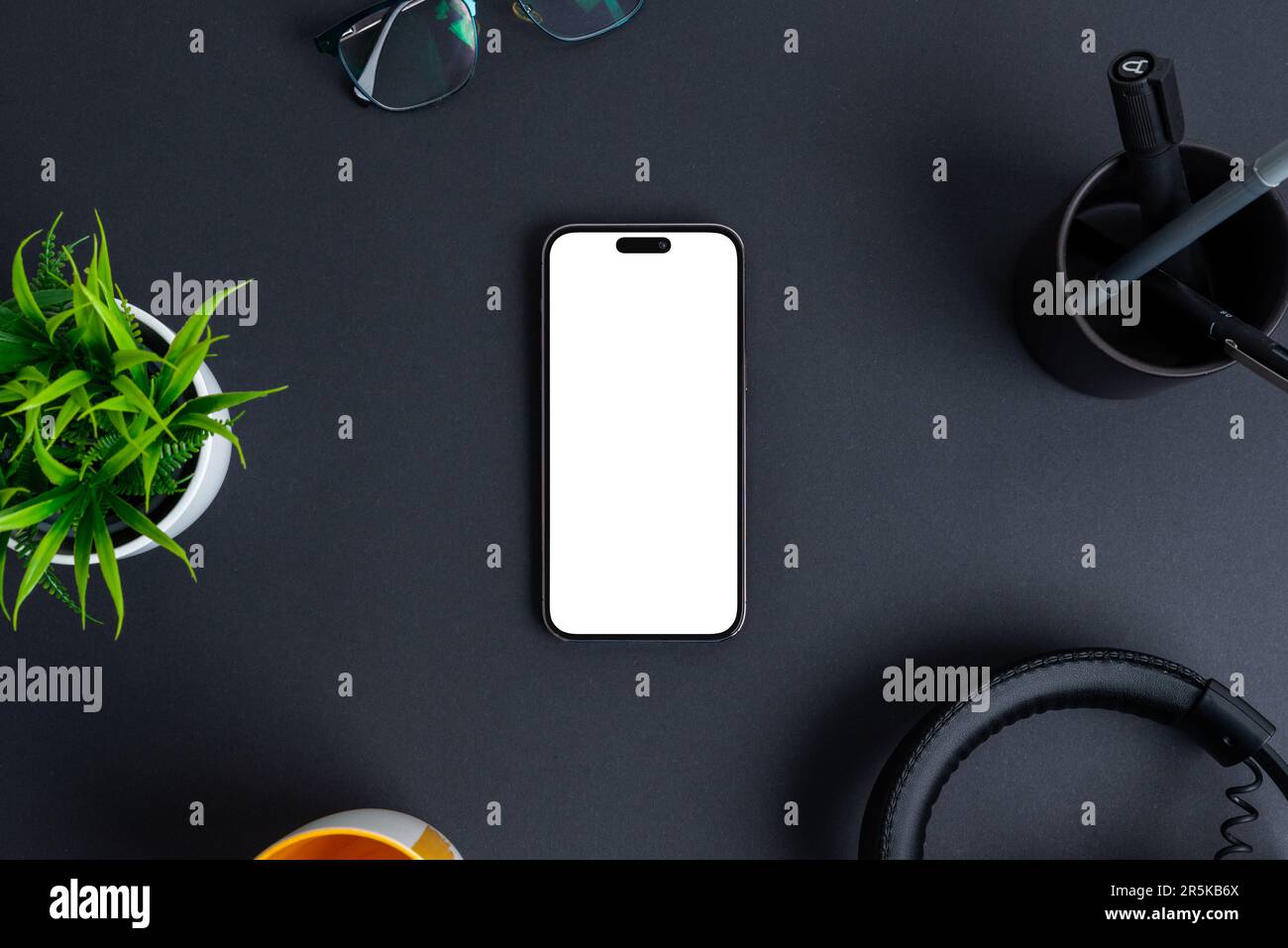 Telefonmodell auf schwarzem Schreibtisch. Isolierter Bildschirm in Weiß für Werbeaktionen im App-Design. Draufsicht, flach liegend Stockfoto