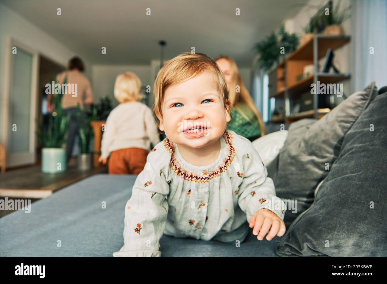 Fröhliche junge Mutter, die mit einem niedlichen Kleinkind spielt und sich auf der Couch im Wohnzimmer ausruht Stockfoto