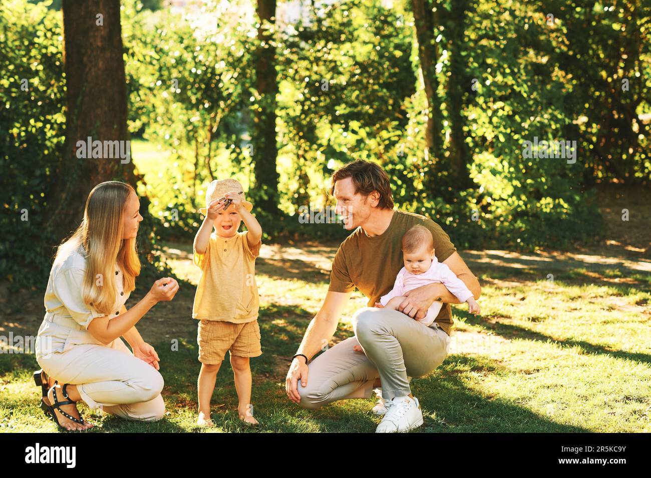 Außenporträt einer glücklichen Familie, die Spaß im Sommerpark hat, ein junges Paar mit einem kleinen Jungen und einem kleinen Mädchen Stockfoto