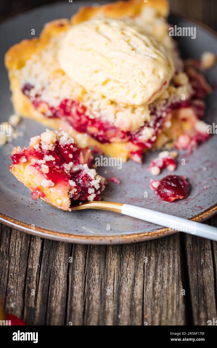 Torte mit saurer Kirschcreme, Creme Patisserie und Krümeln, serviert mit Vanilleeis. Rustikale und stimmungsvolle Atmosphäre und Dekoration. Stockfoto