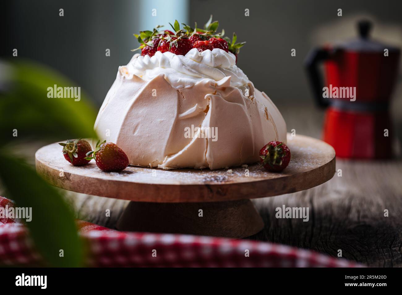 Pavlova-Kuchen mit Erdbeeren auf rustikalem Holztisch. Der Kuchen besteht aus Baiser und Schlagsahne Stockfoto