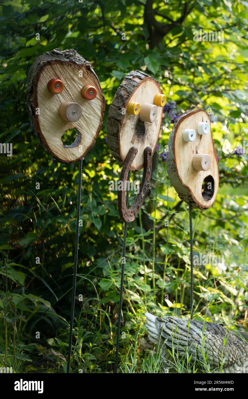 Baumscheibe mit einem Gesicht auf einer Stahlstange als Gartenschmuck. Stockfoto