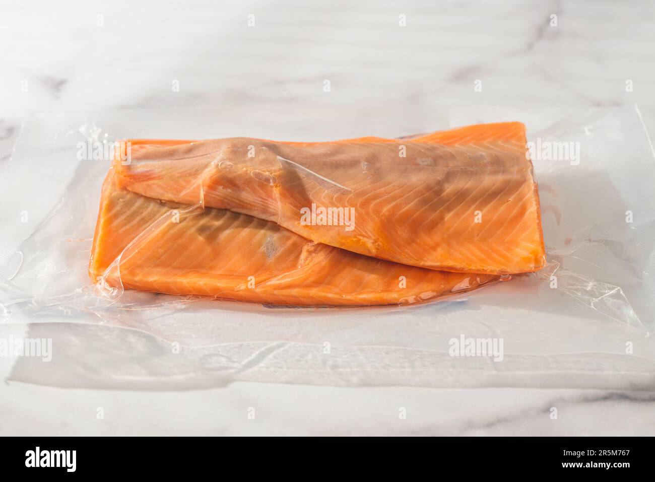 Frischer roher Lachs in einer Plastiktüte Nahaufnahme auf einem Marmorküchentisch, Kopierbereich Stockfoto