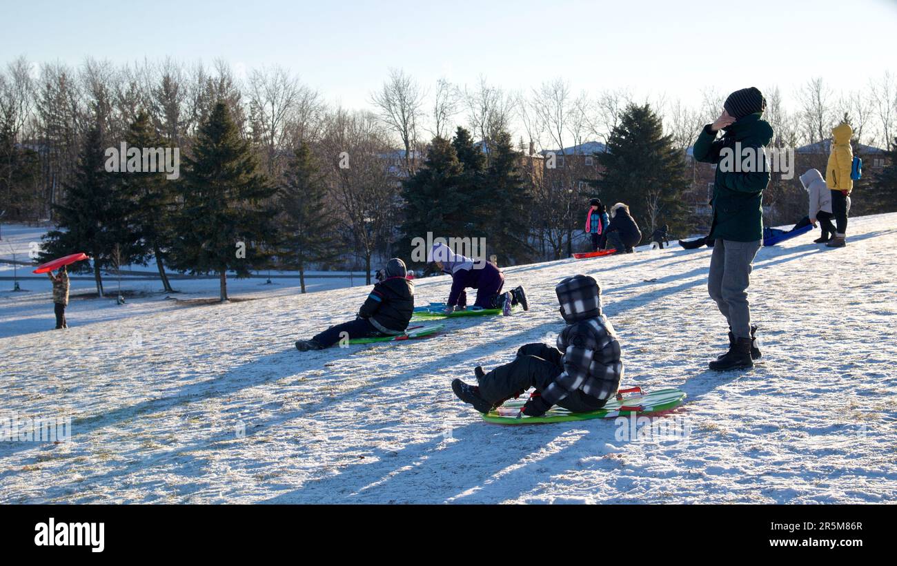 Toronto, Ontario / Kanada - 14. Januar 2023: Wintersport Rodelbahn - Mutter und Sohn spielen Rodelbahn, Winter, draußen, gesunde Lebensweise. Stockfoto