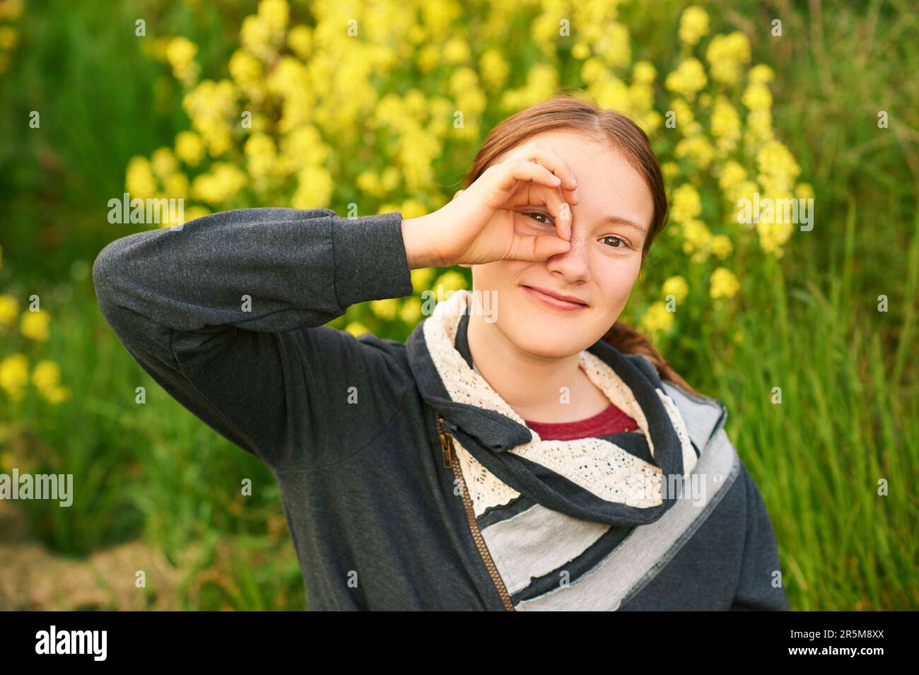 Außenporträt eines jungen Teenagers, das durch die Finger schaut Stockfoto