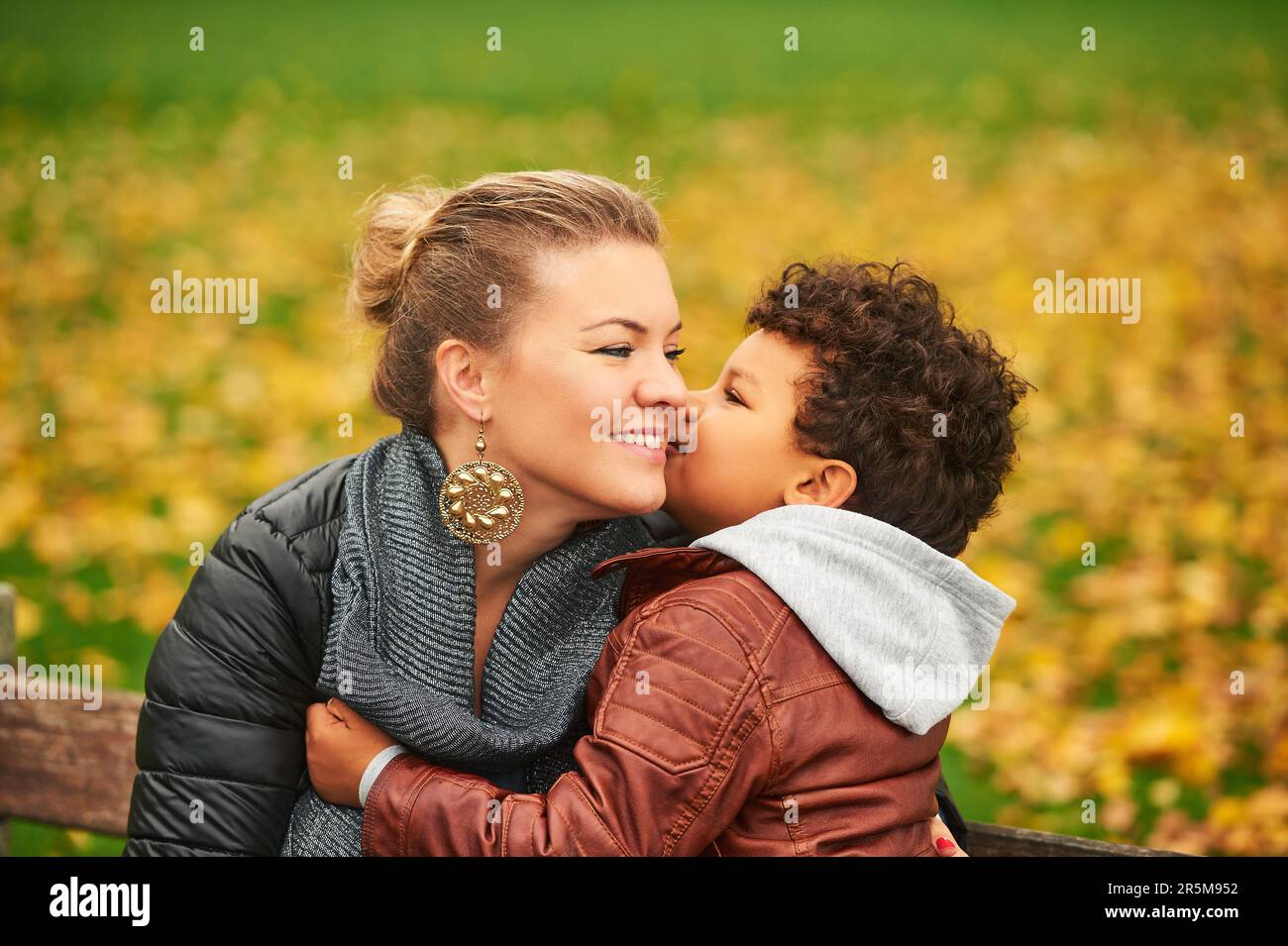 Glückliche junge Mutter hält süße kleine Jungen Familie, die Spaß zusammen draußen an einem schönen Herbsttag hat Stockfoto