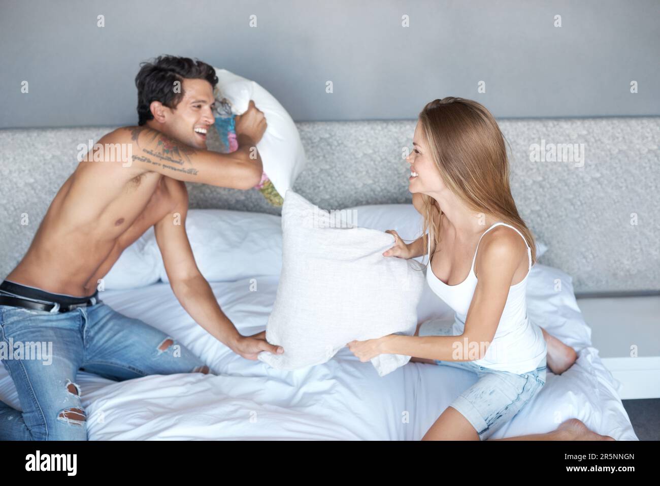 Er liebt ihre Verspieltheit. Ein verspieltes Paar, das sich auf dem Bett mit Kissen prügelt. Stockfoto