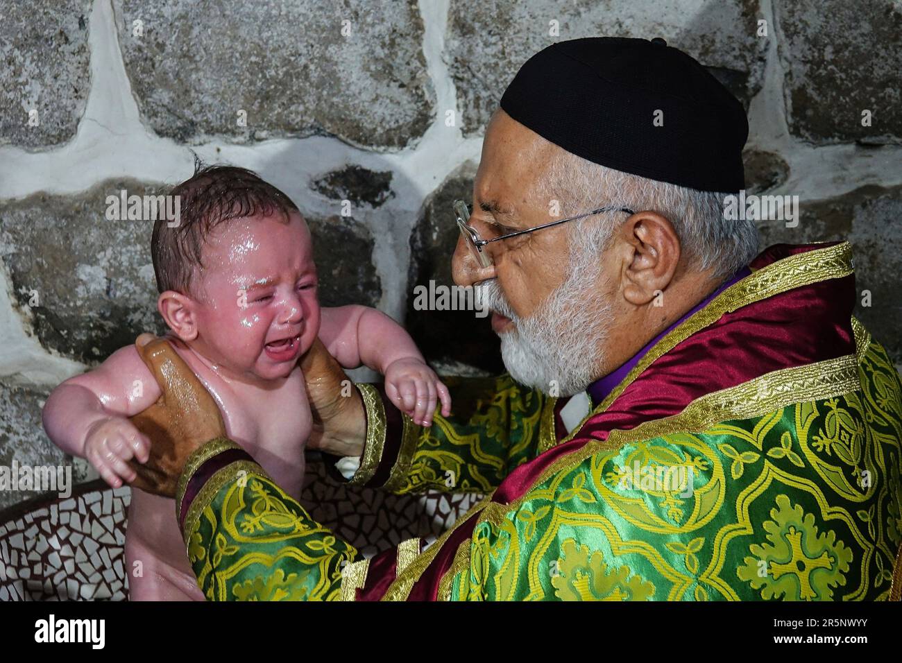 Priester Gabriel Akyuz, der aus der Stadt Mardin zur Taufe nach Diyarbakir kam, wird beim Taufen des Babys gesehen. Die Taufzeremonie der Söhne von Mushe Akbulut und Hulya Karadayi fand gemäß den syrischen Traditionen in der antiken Kirche der Jungfrau Maria von Diyarbak statt. Da die Zahl der Assyrer, die in Diyarbakir leben, so stark zurückgegangen ist, wurden Mushe und Hulya die ersten Assyrer, die nach einer 40-jährigen Pause heirateten. Die Söhne der Familie wurden von Priester Gabriel Akyuz angeführt, der aus der Stadt Mardin kam, um das Ritual in der Jungfrauenkirche zu veranstalten. (Foto: Mehmet Masum Suer/SO Stockfoto