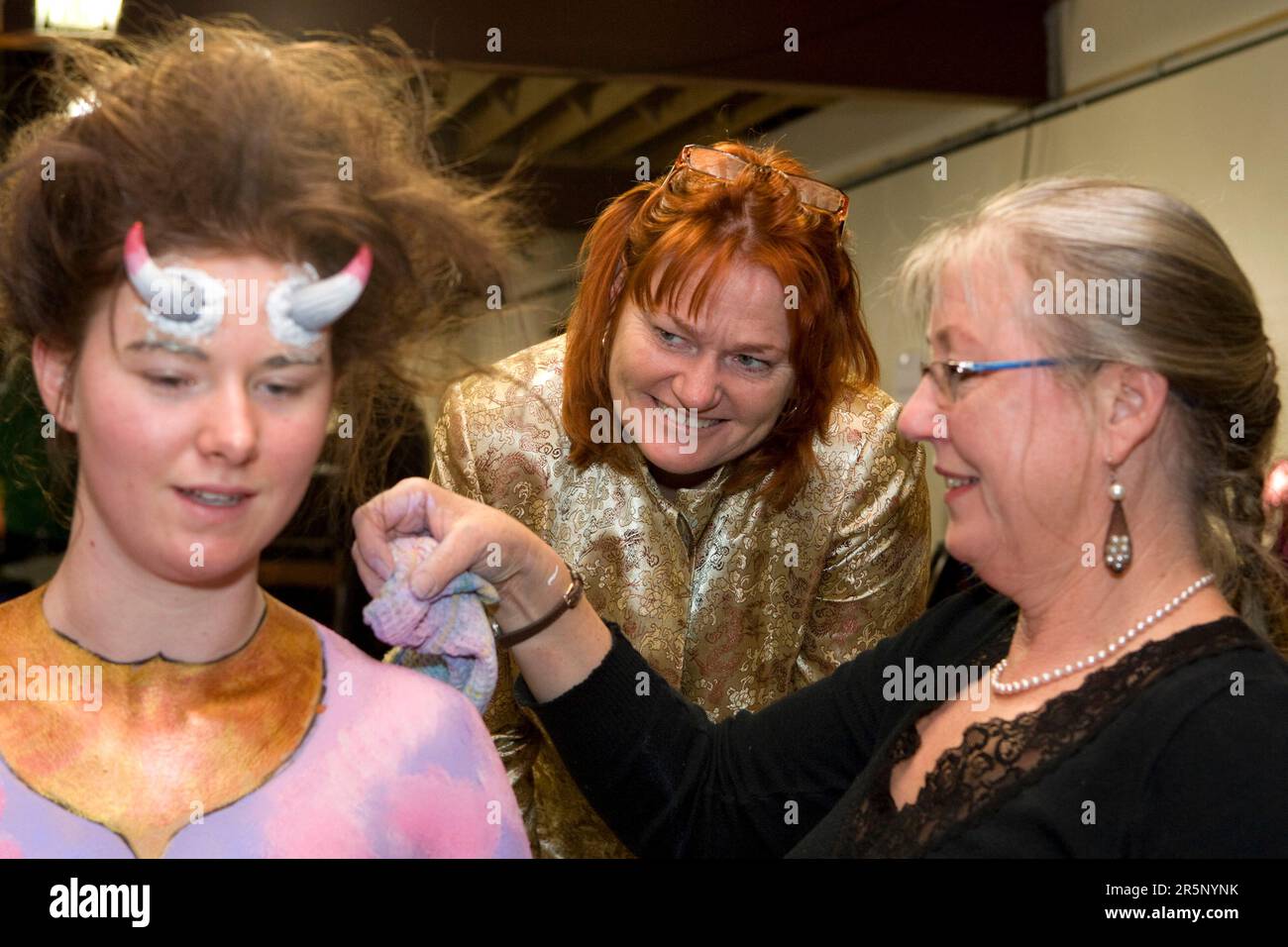 Body Art Creative Director Mem Bourke, Center, beobachtet Helga Strewe bei der Vorbereitung des Modells Rosie Abel für die Kategorie Handgemalt bei den NZ Body Art Awards Stockfoto