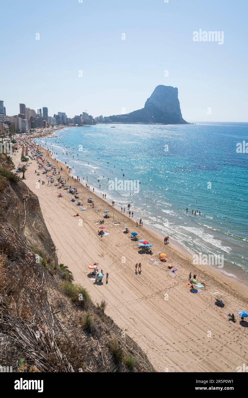 Calpe, Spanien - 19. Juli 2021: Sonniger Strand mit Touristen für Urlaub entlang der Küste von Calpe mit Blick auf die Felsformation 'ifach' Stockfoto