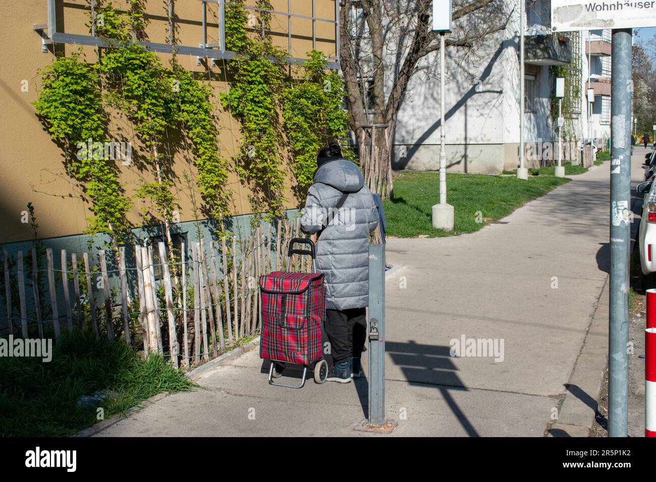 wien, österreich. 5. april 2023 Einkäufer in der Stadt eine Frau steht mit ihrer treuen Trolley-Tasche auf der Straße (Alltag in europa) Stockfoto