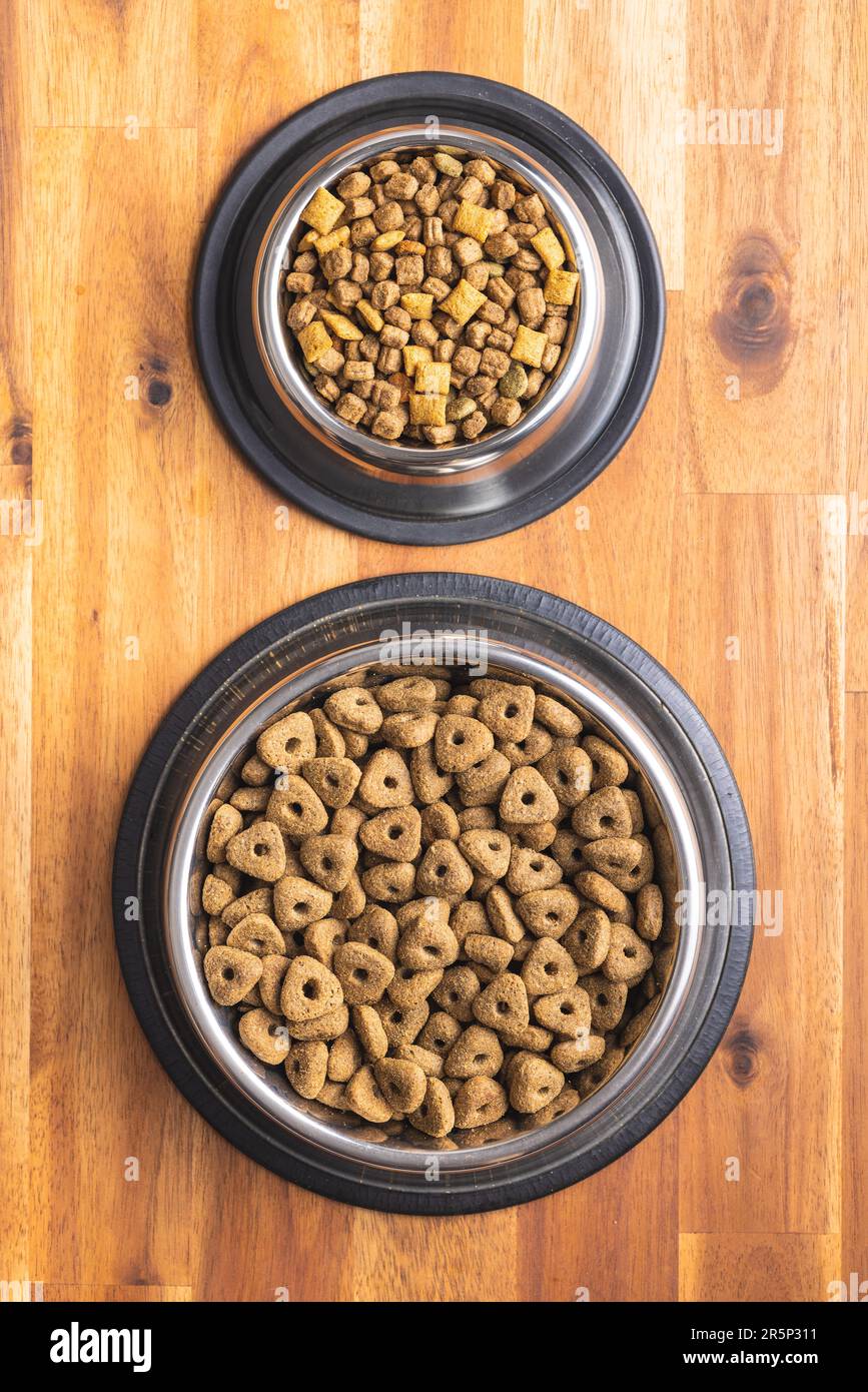 Trockenes Kibble-Tierfutter. Hunde- oder Katzenfutter in der Schüssel auf dem Holztisch. Draufsicht. Stockfoto
