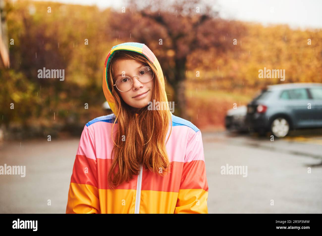 Außenporträt eines hübschen jungen Mädchens mit farbenfrohem Regenmantel Stockfoto