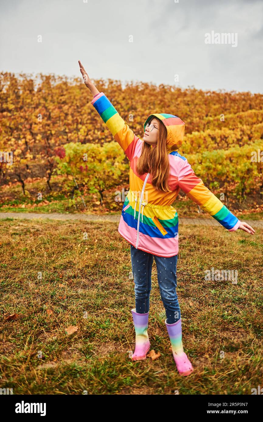 Außenporträt eines hübschen jungen Mädchens mit farbenfrohem Regenmantel Stockfoto