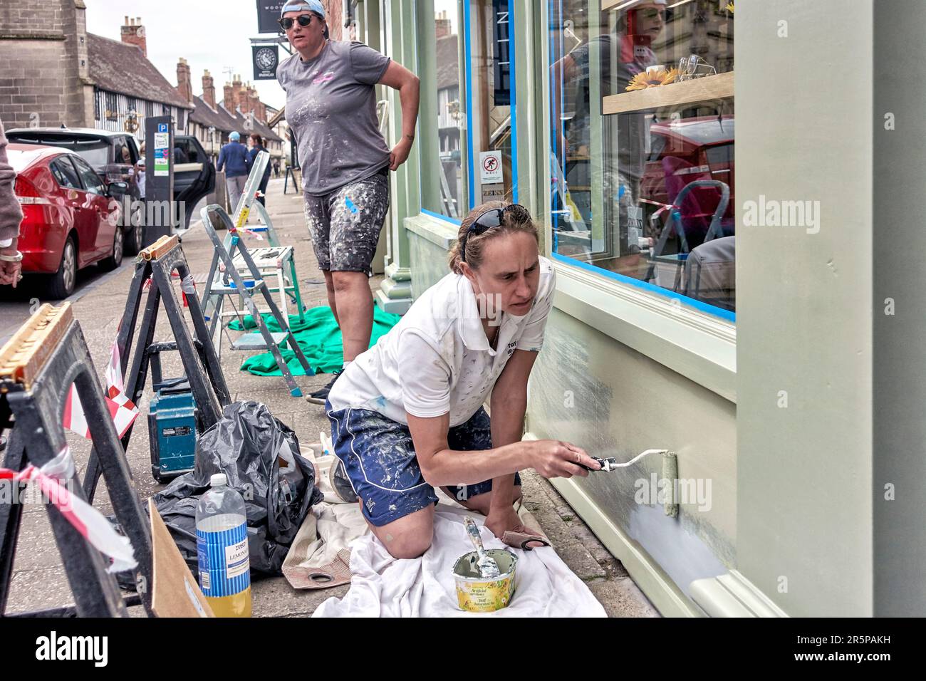Frauen bei der Arbeit im Freien streichen die Außenfassade eines Ladens. England Großbritannien Stockfoto