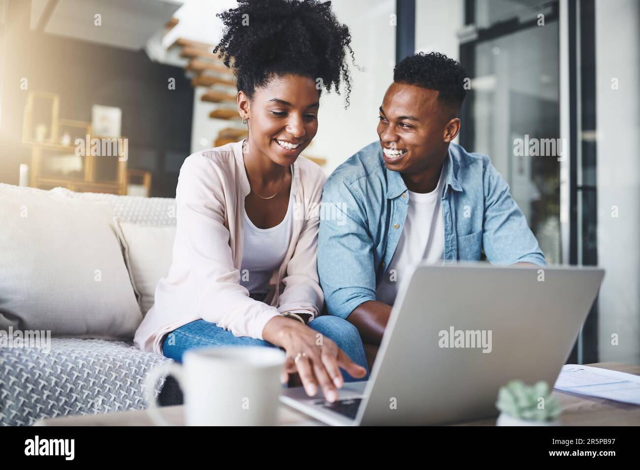 Es gibt etwas, das es wert ist, online geteilt zu werden. Ein glückliches junges Paar, das zu Hause einen Laptop zusammen auf dem Sofa benutzt. Stockfoto