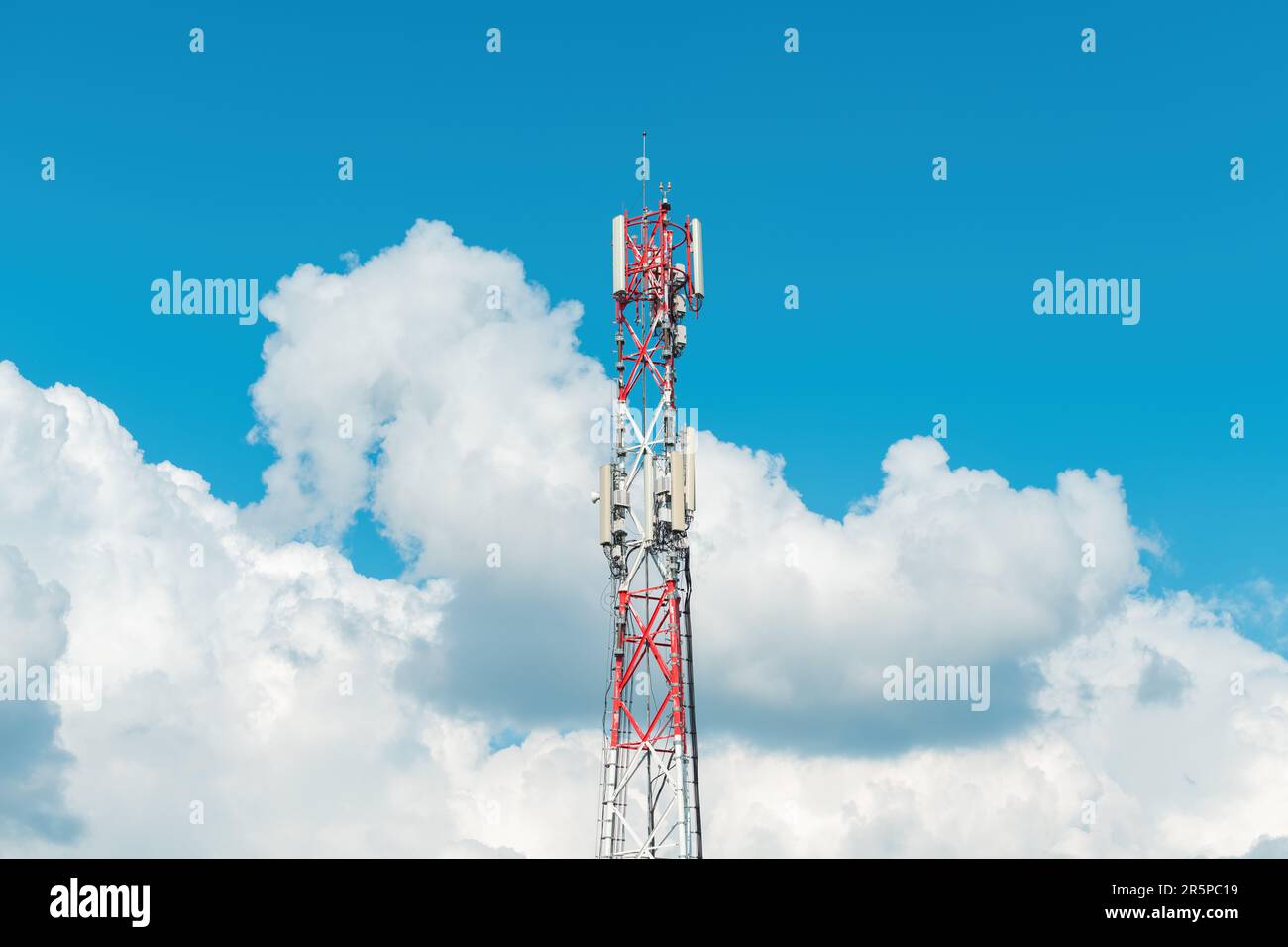 Mobilfunk-Basisstation auf Kommunikationsturm gegen bewölkten Sommerhimmel Stockfoto
