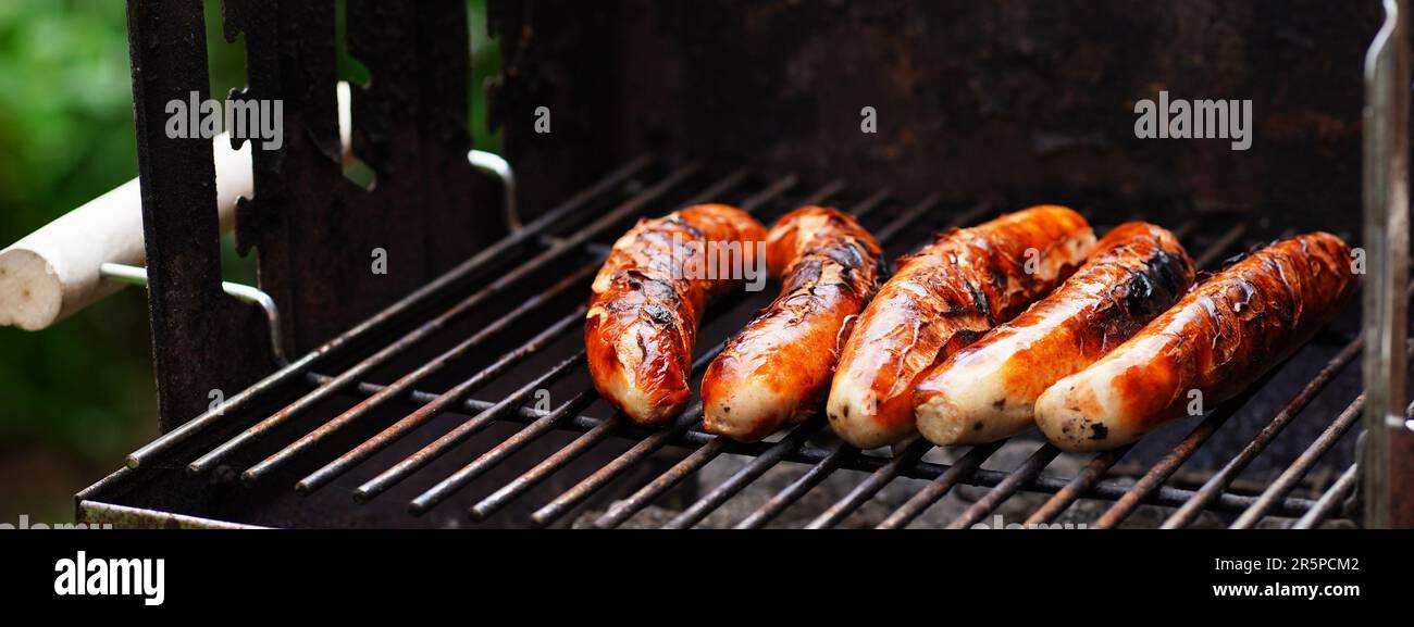 Kochen von Speisen im Garten. Auf dem Grillrost stehen frisch gegrillte traditionelle thüringer Würste, die im Freien in Deutschland gegrillt werden können Stockfoto