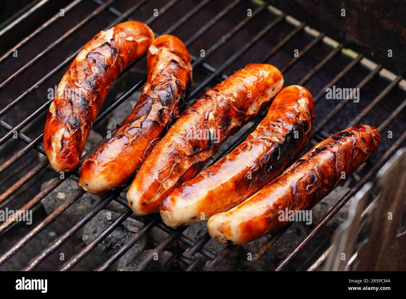 Kochen von Speisen im Garten. Auf dem Grillrost gibt es frisch gegrillte traditionelle Nürnberger Würste, die verzehrfertig sind - Barbecue-Grillen im Freien in Deutschland Stockfoto