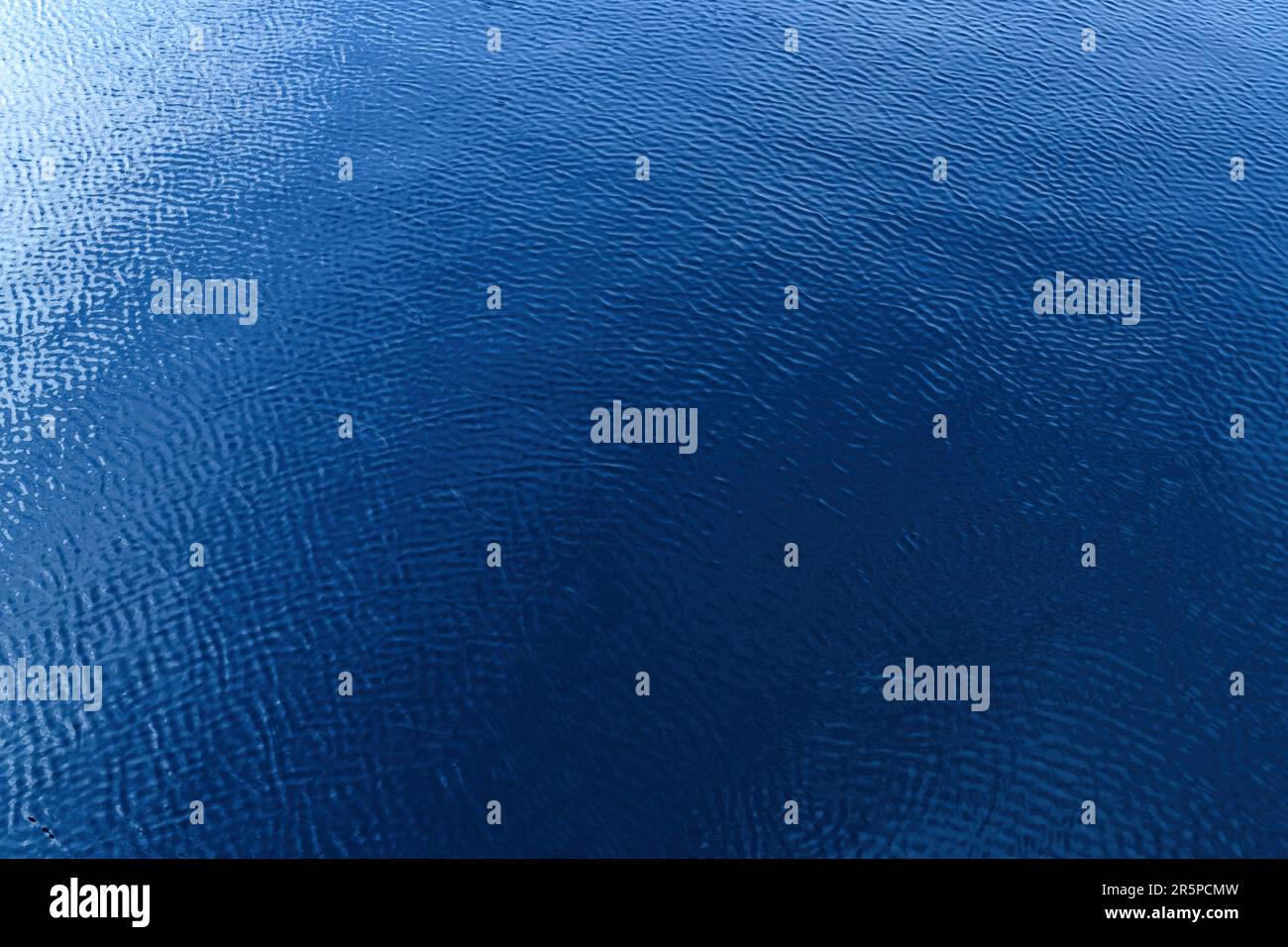 Blaue Wasseroberfläche mit Wellen und Lichtreflexion. Textur des sauberen Süßwassers des Nissan-Flusses in der Stadt Halmstad in Schweden. Selektiver Fokus Stockfoto