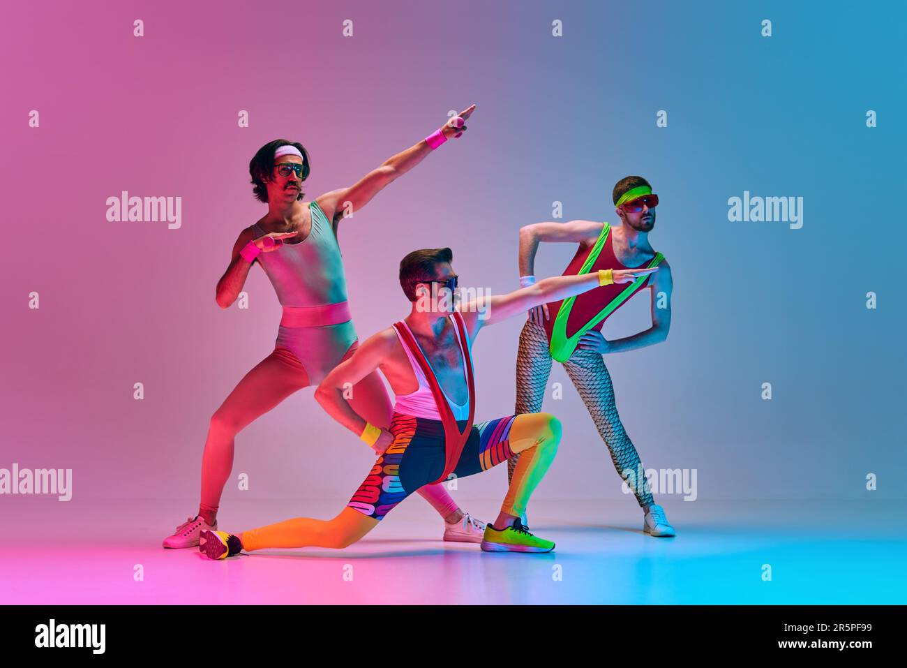 Lustiges Bild von drei Männern in stilvoller, klassischer Sportbekleidung,  Aerobic und Gymnastik vor einem gradientenblauen, rosa Studiohintergrund  Stockfotografie - Alamy
