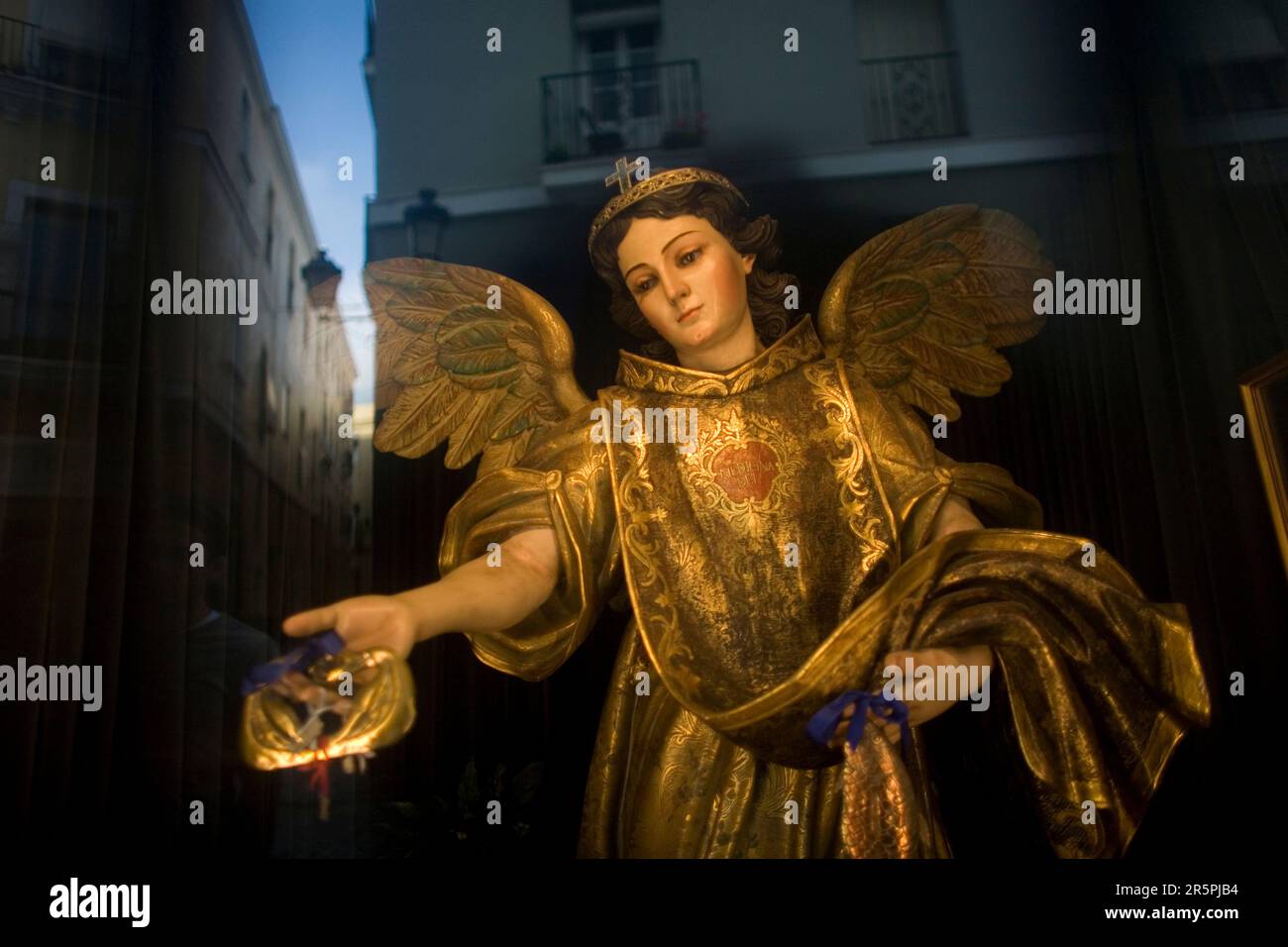 Hinter einem Fenster befindet sich eine Statue von St. Raphael Arcangel, während sich die Stadt Cadiz in Andalusien, Spanien, widerspiegelt. Stockfoto
