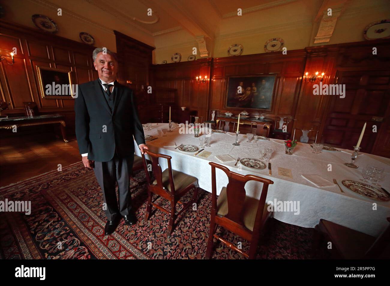 Ein kostümierter Butler begrüßt Besucher im historischen Speisesaal des Dunham Massey, einem Landhaus des National Trust in Cheshire, England, Großbritannien Stockfoto
