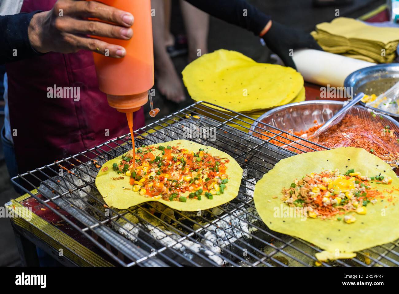 Gegrillter vietnamesischer Pfannkuchen mit Eiern, Würstchen und Saucen auf dem vietnamesischen Nachtmarkt beim Food Festival Stockfoto