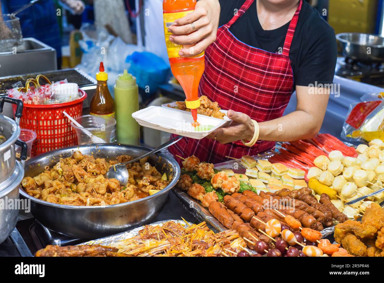 Vietnamesische Frau serviert Hühnerpfoten in einer Plastikbox mit Chili auf dem vietnamesischen Nachtmarkt Stockfoto