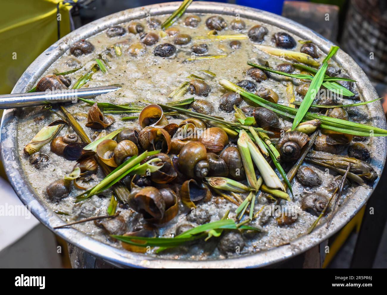 Gedünstete Schnecken mit Gemüse und Zitronengras in Bambus auf dem vietnamesischen Nachtmarkt Stockfoto