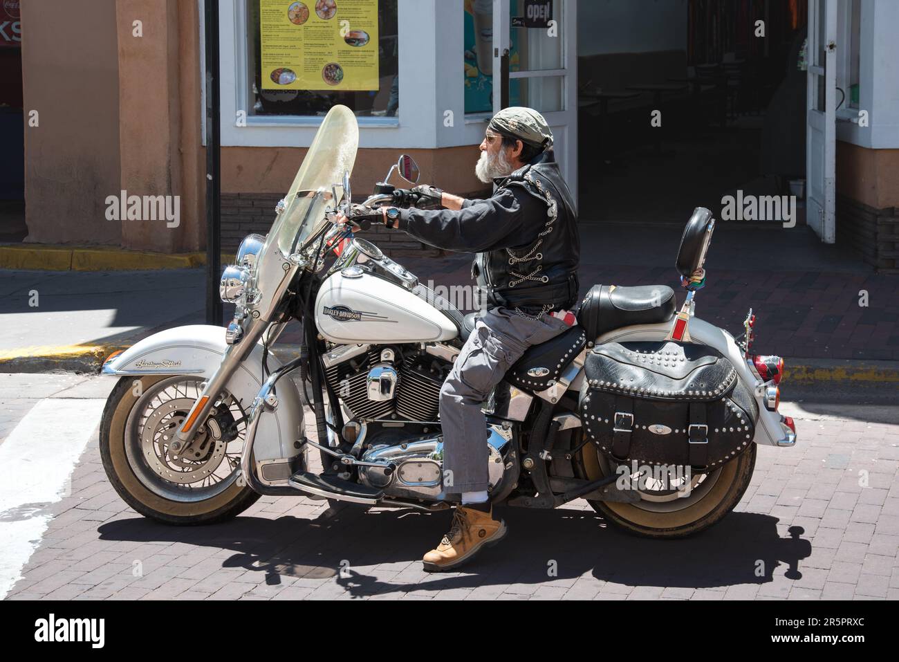 Älterer Mann mit weißem Bart auf einem Harley Davidson Motorrad, hielt an einem Straßenübergang am Santa Fe Plaza, Santa Fe, New Mexico, USA. Stockfoto