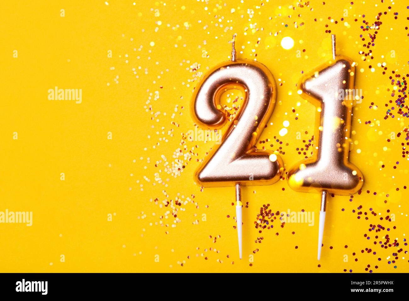 21 Jahre Feier. Grußbanner. Goldene Kerzen in Form von Nummer 21 auf gelbem Hintergrund mit Konfetti. Stockfoto