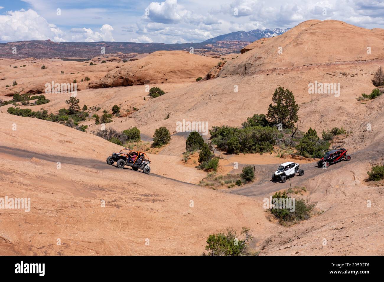4WD UTVs/OHVs erklimmen einen steilen Sandsteinhang der Navajo auf dem Hell's Revenge OHV Trail in der Nähe von Moab, Utah. Stockfoto