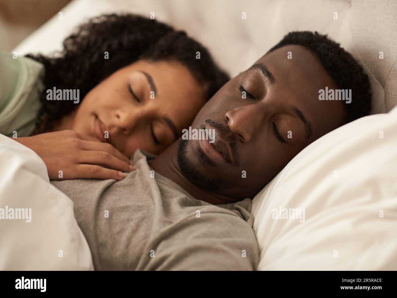 Ein junges, multiethnisches Paar schläft morgens im Bett Stockfoto