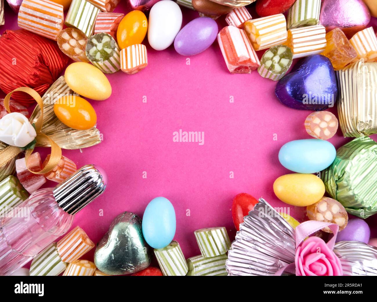 Sugar Feast Social Media Post Hintergrund mit Kopierraum. Rosafarbener Hintergrund. Bunte Süßigkeiten, eingepackte Luxusschokolade. Mandelbonbons. Zucker. Stockfoto