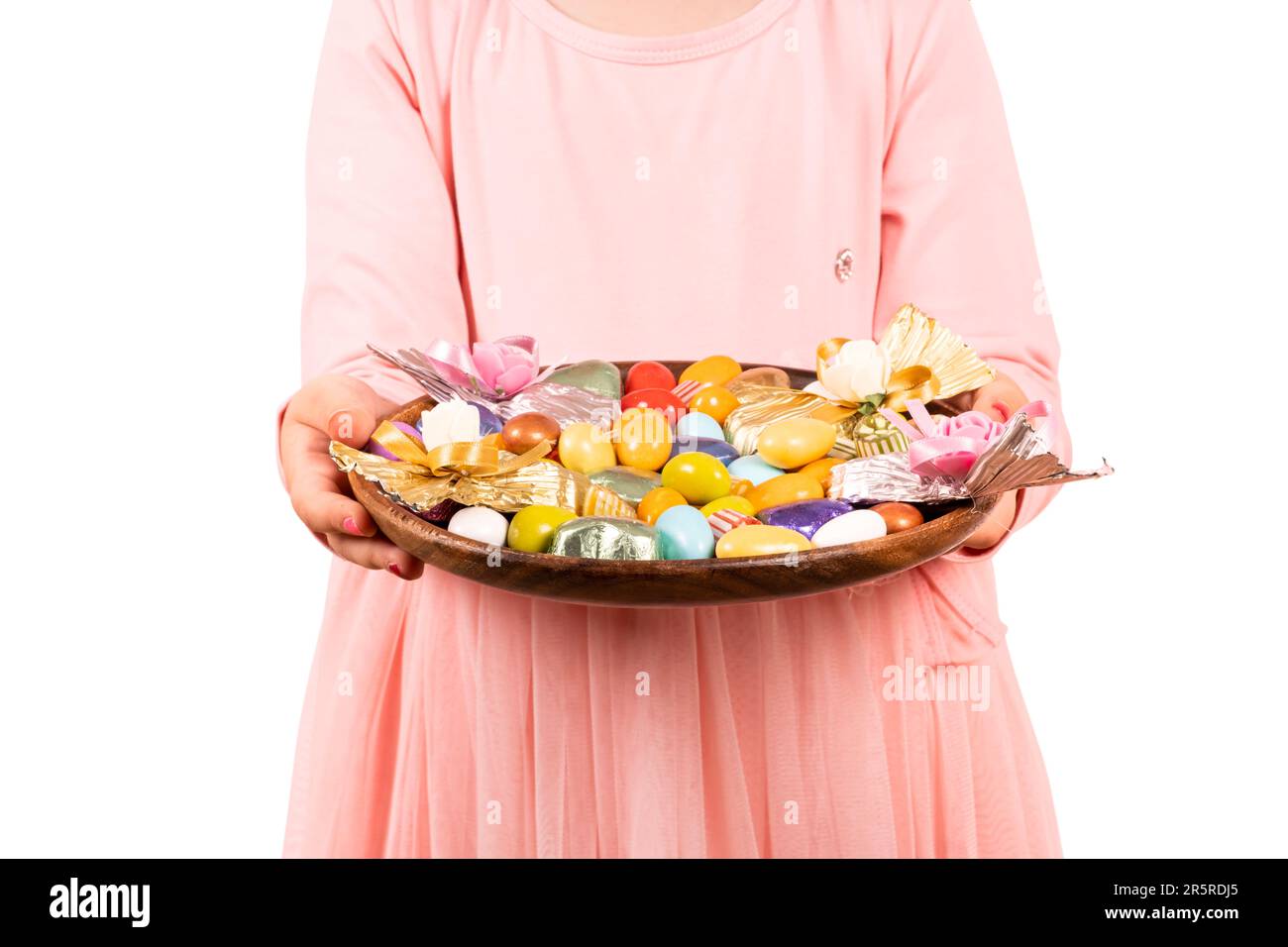 Mädchen in rosa Kleid mit gemischten Süßigkeiten. Luxuriöse Schokolade, Mandeldragee in Tablett. Isolierter weißer Hintergrund. Kopierbereich. Stockfoto