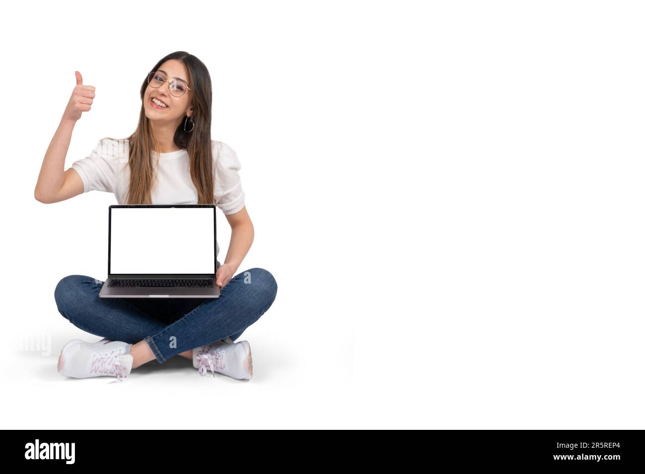 Fröhliche kaukasische Brünette mit Laptop-Mockup. Leeres, modernes Notebook mit weißem Bildschirm. Lächelnd, Daumen hoch, Webseite wird empfohlen. Stockfoto