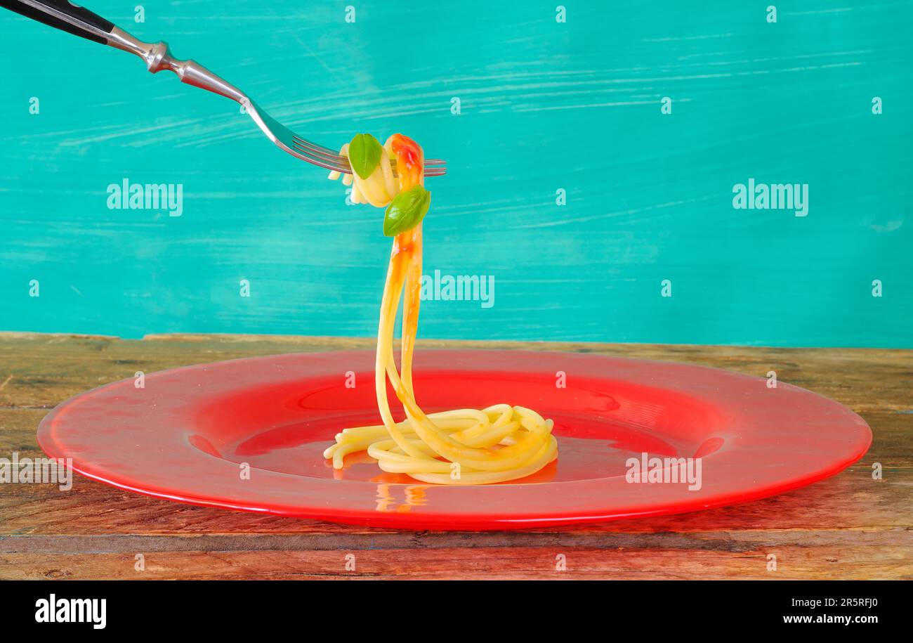 Spaghetti mit Suace und Basilikum, die an einer alten Gabel hängen, italienische Küche, italienisches Restaurant, Kochkonzept Stockfoto