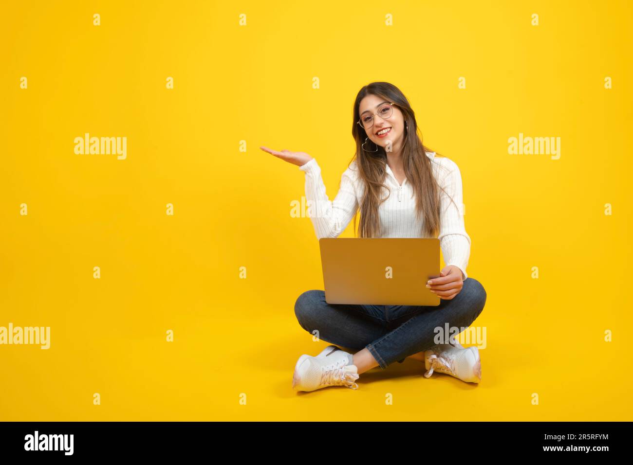 Frau mit offener Hand, Werbevorlage vorführen, Werbeanzeige, Werbeanzeige, Bannerdesign-Idee. Fröhliches Weißes Mädchen, das auf dem Boden sitzt. Stockfoto