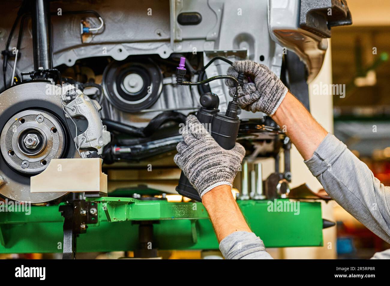 Arbeiter installiert Kunststoffkiste auf der Fahrzeugseite in der Werkstatt Stockfoto