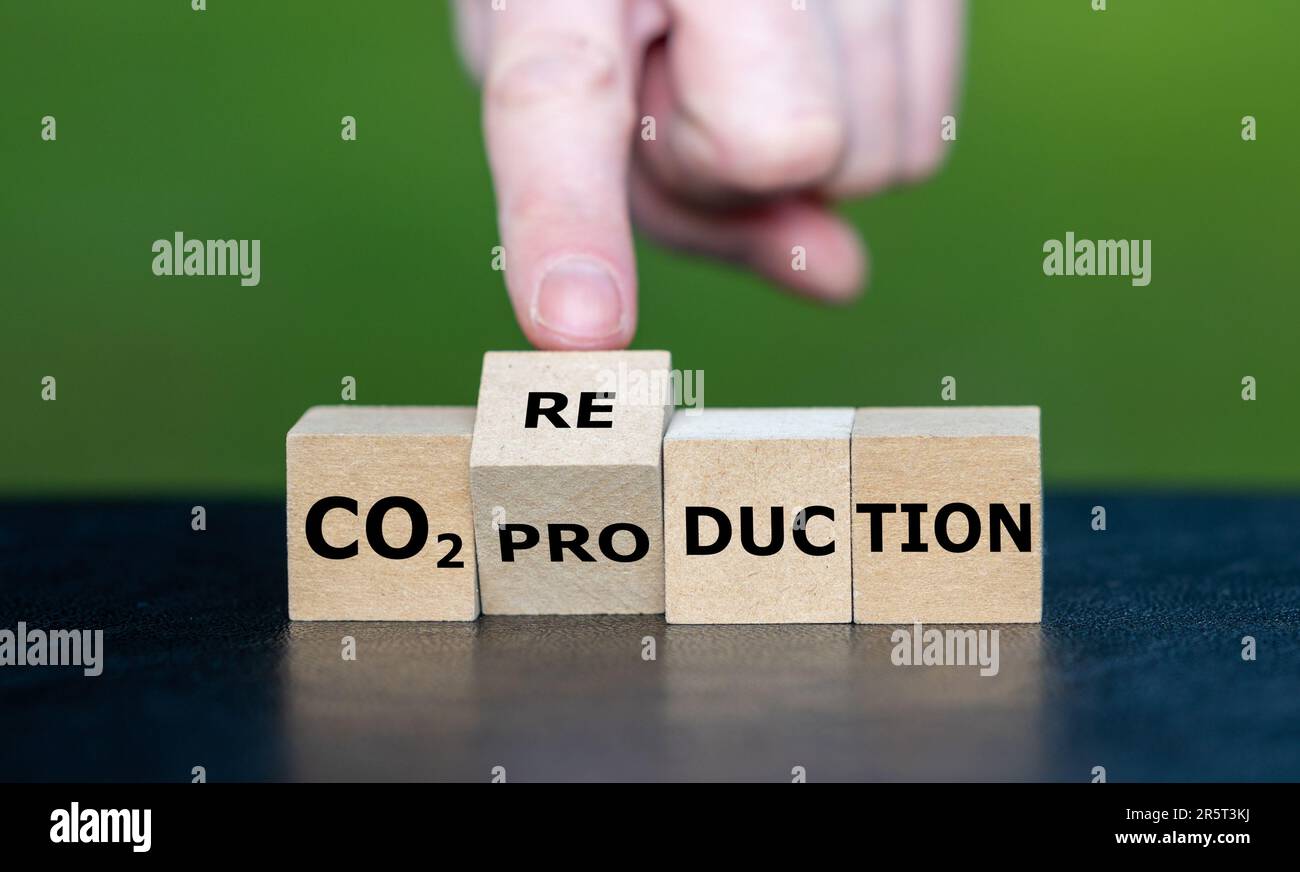 Die Hand dreht den Holzwürfel und ändert den Ausdruck „CO2-Produktion“ in „CO2-Reduktion“. Stockfoto