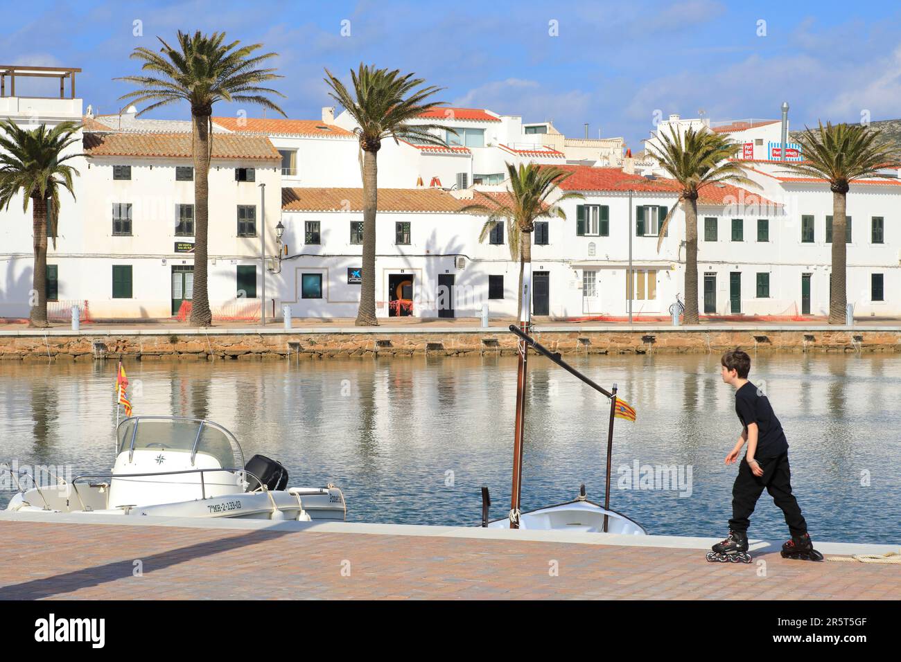 Spanien, Balearen, Menorca, Fornells, Junge auf Rollerblades am Hafen Stockfoto