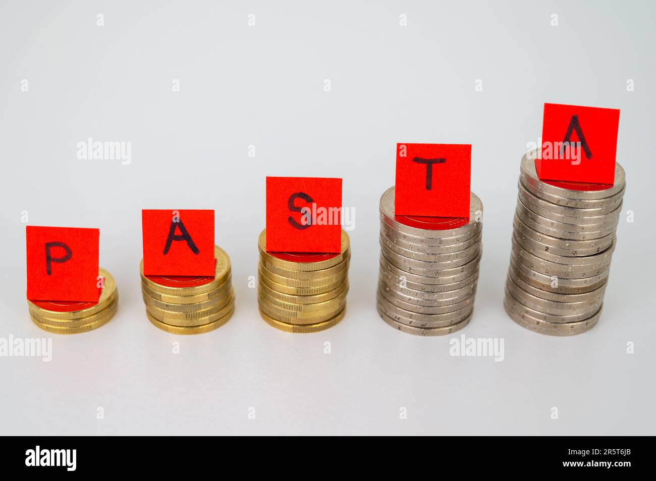 Stapel von Münzen und über Tickets, die das Wort „Pasta“ buchstabieren. Anstieg der Pasta-Preise. Erhöhung des Preises für Weizen. Stockfoto