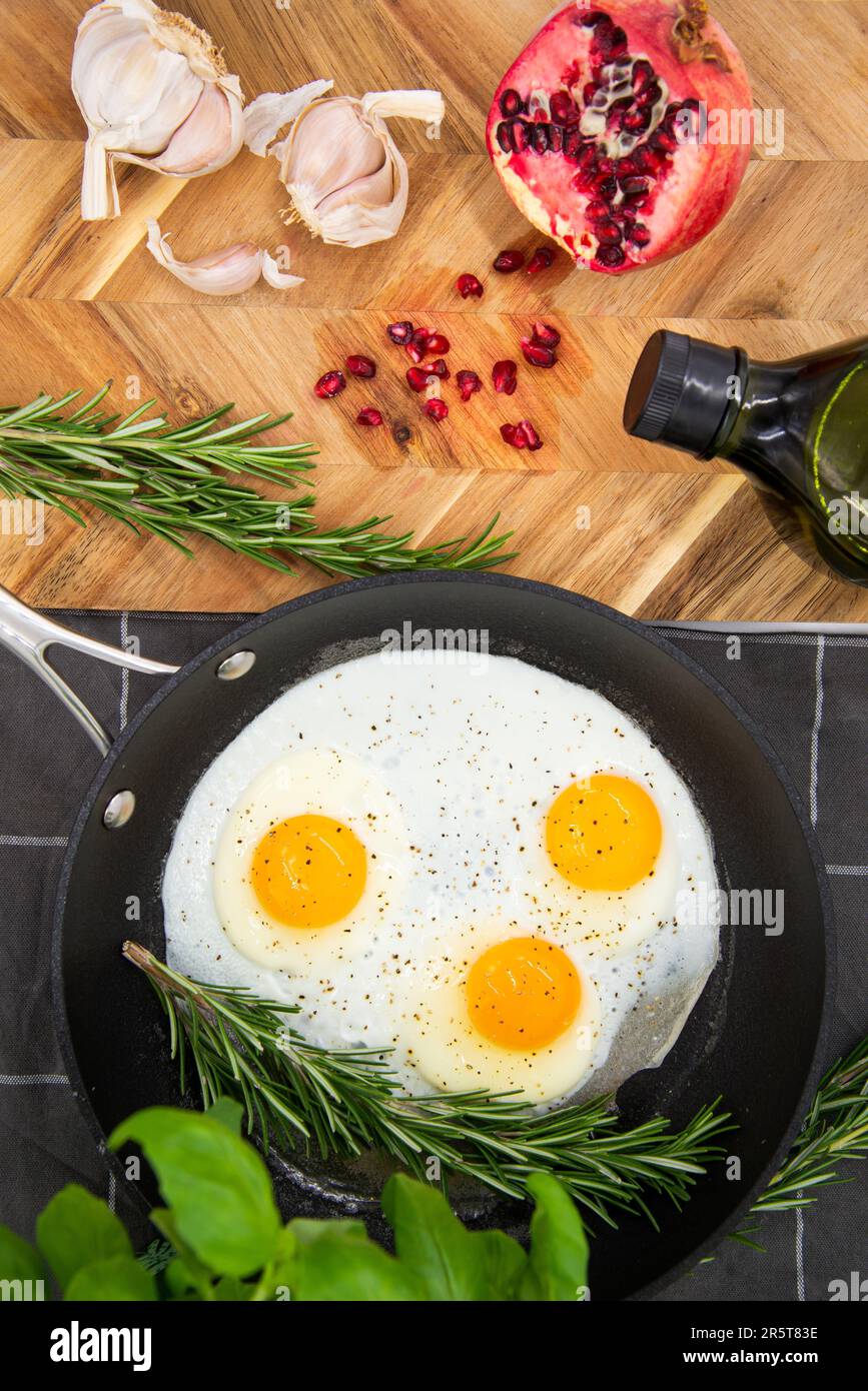 Eine Nahaufnahme einer Edelstahlpfanne mit drei frisch gebratenen Eiern,  die auf einer Küchentheke liegen Stockfotografie - Alamy