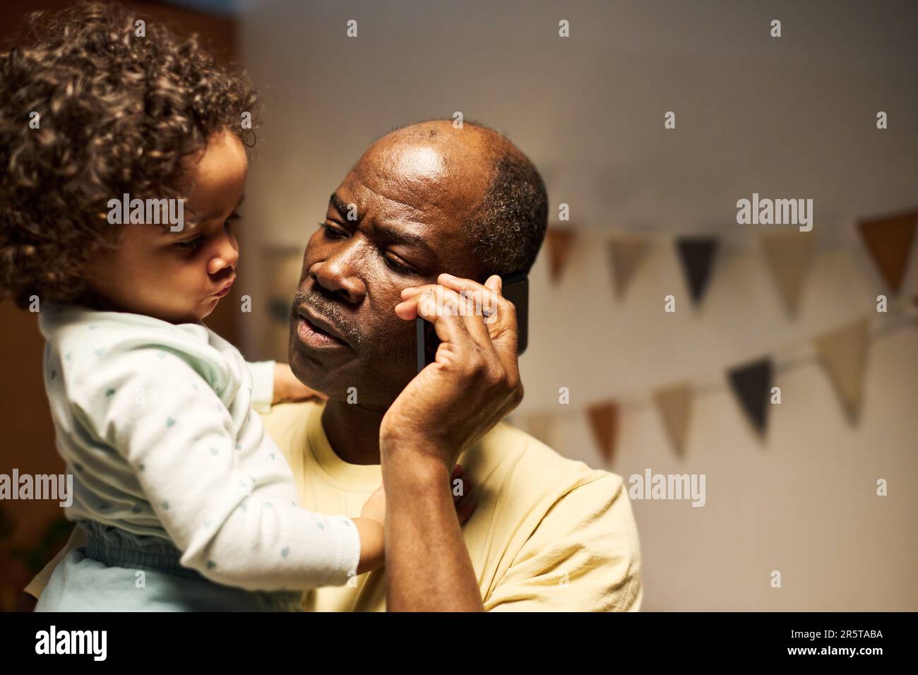 Afroamerikanischer Vater, der sich mit seinem Baby auf dem Handy unterhält Stockfoto